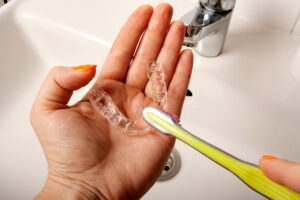 マウスピースを歯ブラシで洗う女性の手元
