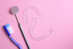 ピンクの背景と2枚のマウスピースと歯科用器具