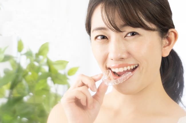 マウスピース矯正の装置を装着しようとしている女性