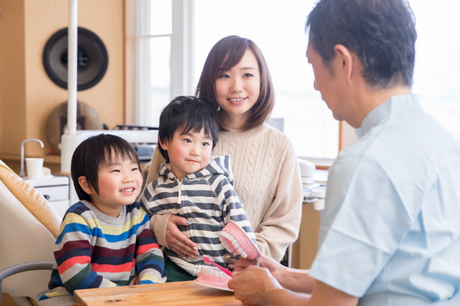 フッ素の効果を説明する歯科医師と話を聞く親子