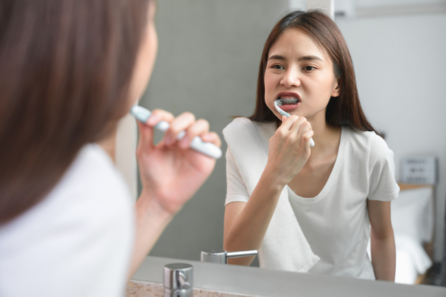 難しそうに歯磨きをするワイヤー矯正中の女性