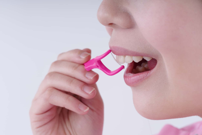 クリーニング時の痛みを軽減するためにフロスでセルフデンタルケアをしている様子