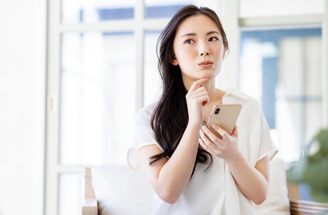 マウスピース矯正で抜歯が不要なケースをスマホで調べる女性