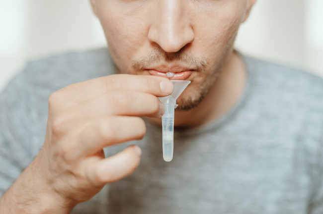唾液を容器に入れる男性