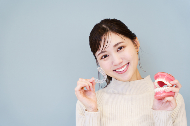 マウスピースを手に笑顔を見せる女性