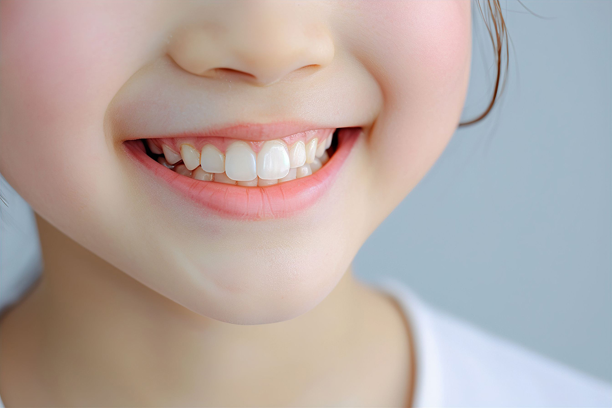 白くきれいな歯で笑顔を見せる子どもの口元