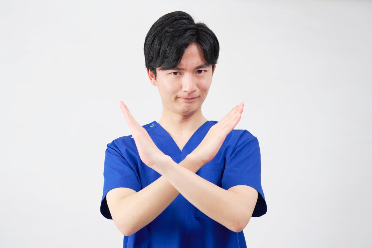 両手でバツマークを作っている歯科医師