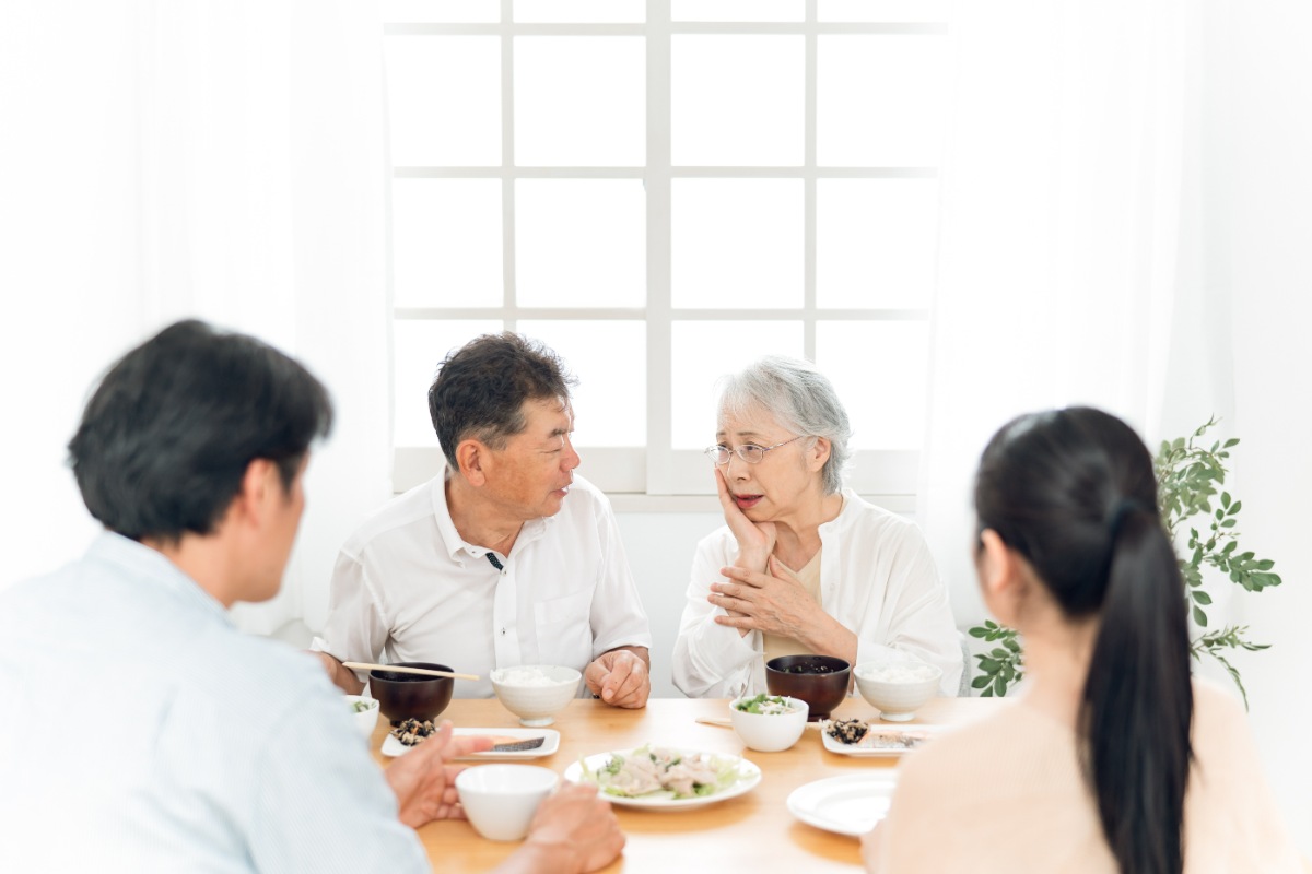 食事中に入れ歯がフィットせず食べにくいことを夫に話す妻